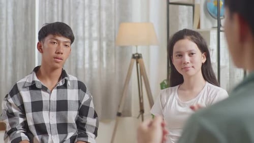 Asian Teen Group Sitting And Discussing At Home. Back View Of A Boy In Gray Shirt Motivating