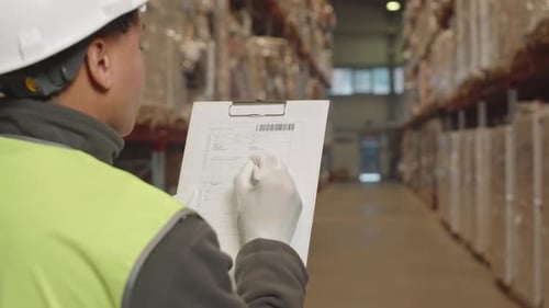 Female Warehouse Supervisor Checking Invoice Document