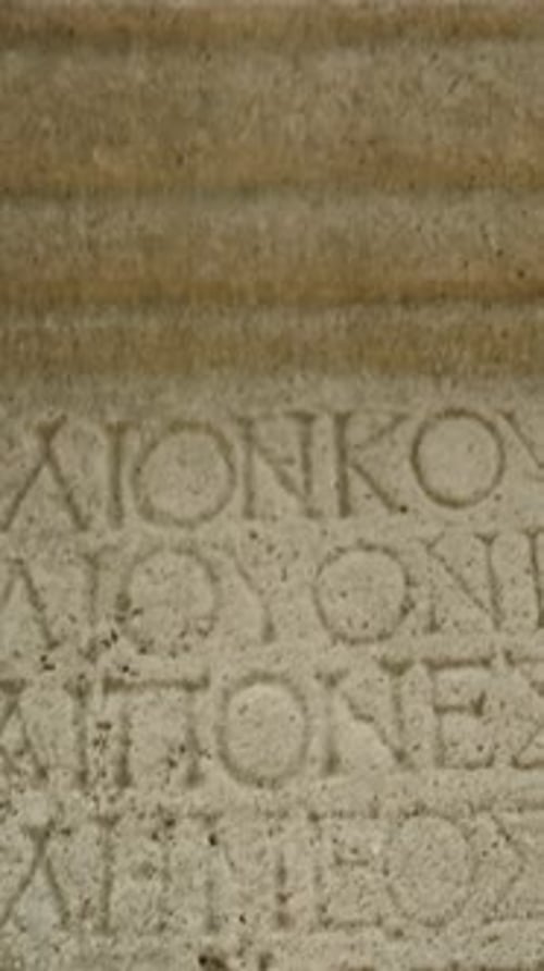 Vertical video. Stone column with ancient Greek inscriptions carved into it, archaeological