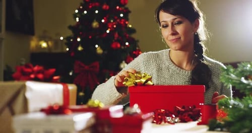 Woman Finishing Wrapping Christmas Gifts at Home
