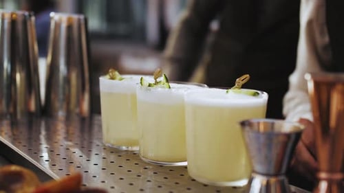 Bartender Garnishing Cocktails on Countertop with Lemon