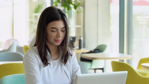Woman Working on Laptop in Bright Cafe