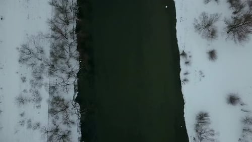 Luftaufnahme eines Flusses im Winter mit schneebedeckten weißen Ufern