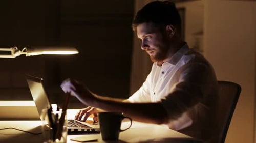 Focused Man Works Late Night at Desk