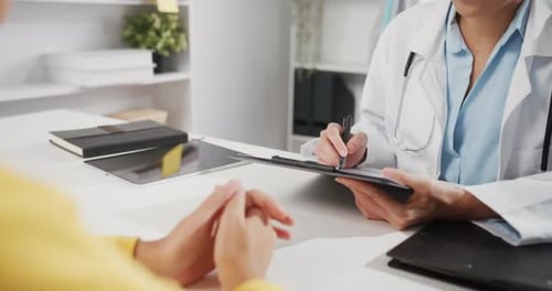 Doctor Writing on Clipboard During Patient Visit