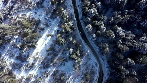 Aerial view of winter road in snow covered mountain forest
