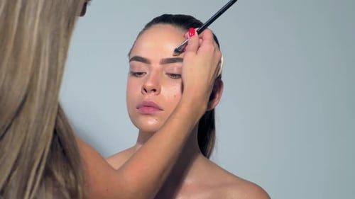 The Artist is Applying Eyeshadow on Her Eyebrow with Brush
