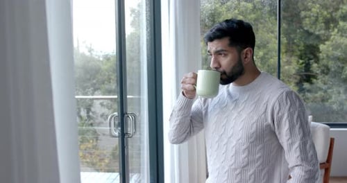 Man Sipping Coffee in Modern Home by Window