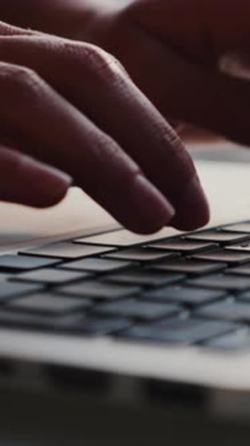 Female hands typing on laptop computer keyboard, using touchpad. Vertical video