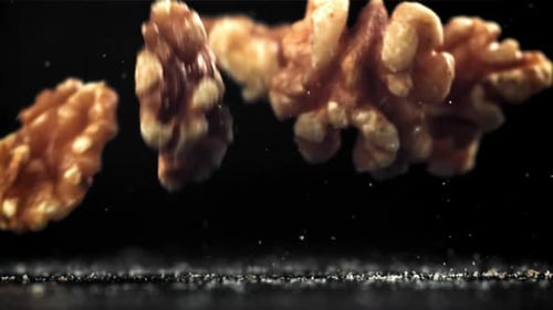 Walnuts Falling in Slow Motion on Dark Surface