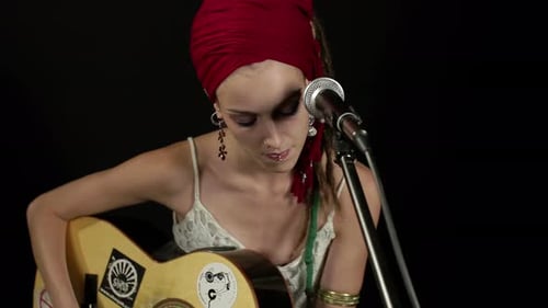 Female Guitarist Singing into Microphone in Studio