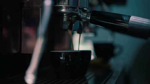 Nahaufnahme eines frischen, duftenden Kaffees, der aus einer Kaffeemaschine in eine Tasse einer Bestellung in einer Bar gegossen wird