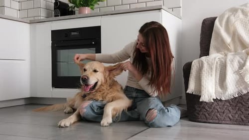 Woman Playing with Golden Retriever Dog in Kitchen