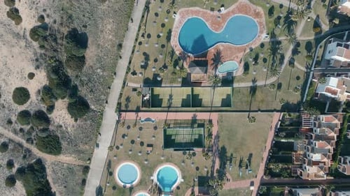 Rising aerial view above Cadiz hotel tennis courts and crystal clear swimming pools resort