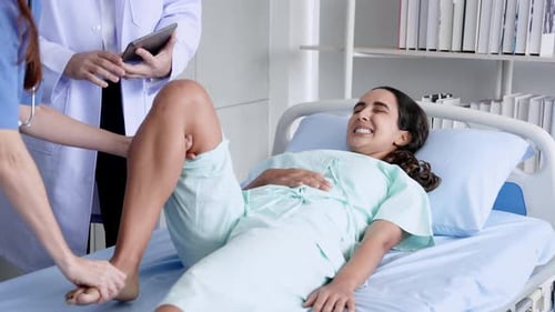 Woman Receiving Leg Examination in Hospital Bed