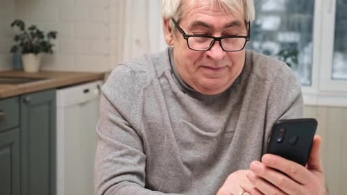 Man Uses Smartphone in Bright Kitchen Area