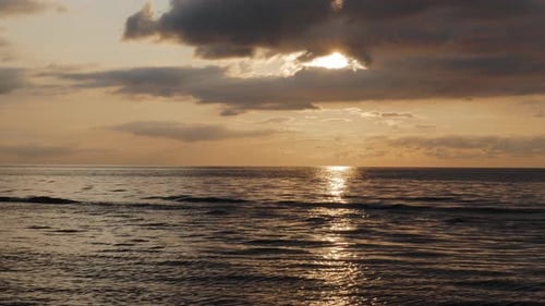Sunset over sea, ocean water with calm waves and beautiful light, steady shot