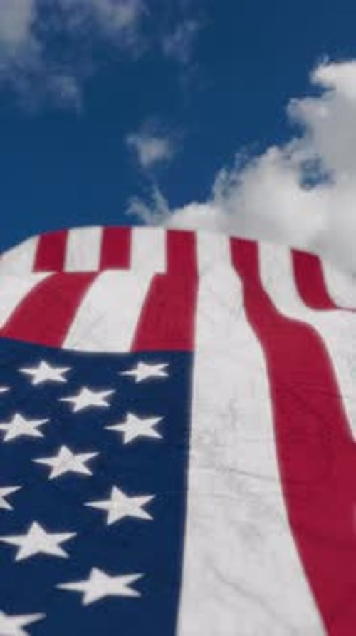 Vertical video national flag of United States of America flutters in the wind on blue sky background