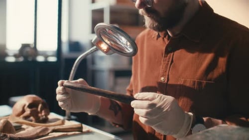 Archaeologist Inspecting Ancient Wooden Artifact under Magnifying Lamp