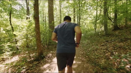 Medium shot young male running through forest