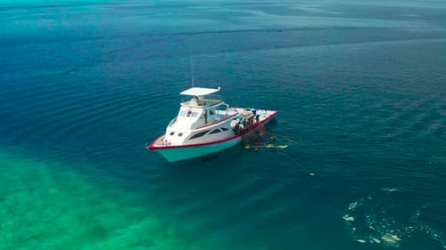 Fishermen on a White Boat Take Out Fishing Nets with Caught Fish Near a Local Island Ukulhas in the