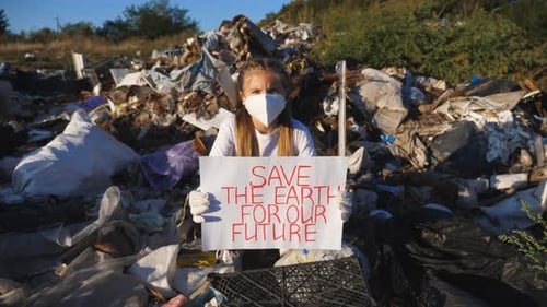 Girl Holds Save Earth Sign in Landfill