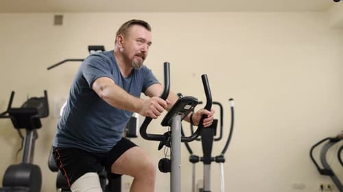 Man Exercising on Stationary Bike in Fitness Center