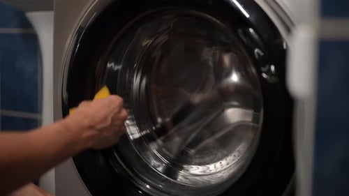 Hand Cleaning Washing Machine Inside with Sponge