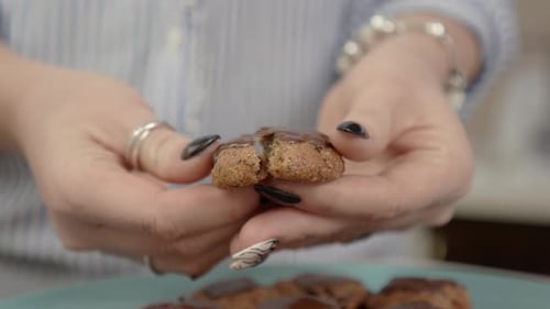 Woman Breaks Chocolate Cookie in Half