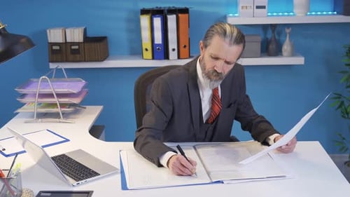 Mature businessman working in office making and checking project drawings with focus.