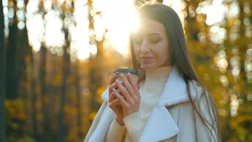 Woman Enjoying Coffee in Autumn Park at Sunset