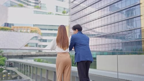 Rear view of businessman and woman partner working outdoors in the city.