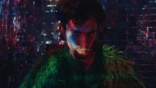 Man in Faux Fur Coat Poses Against Mirror Wall