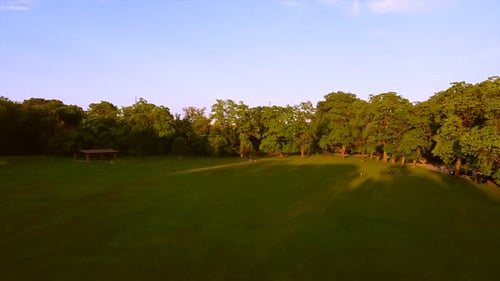 Sonnenuntergang mit Leuten, die Fanaktivitäten im Park haben. Drohnenblick aus der Luft auf die grüne Landschaft des Parks
und