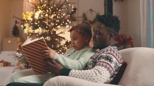 Father and Child Reading Book at Christmas Time