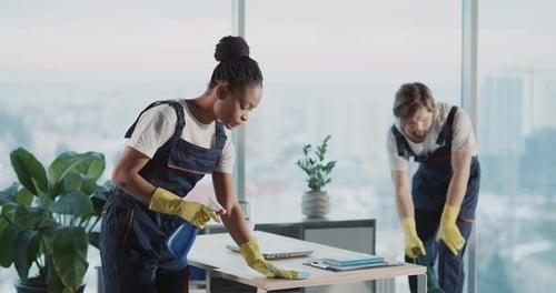 Services de nettoyage Couple afro-américain, belle femme concentrée, désinfectant une table d'ordinateur