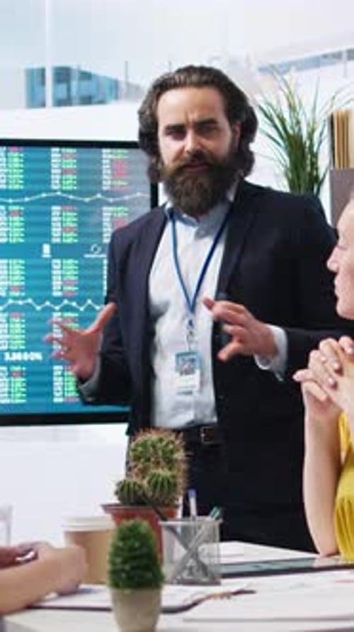 Vertical Video Financial Advisor Looking at Stock Exchange Volatility on Big Screen with Clients