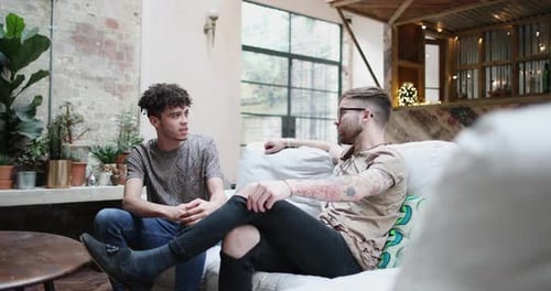 Two Young Men Chatting on Couch Indoors