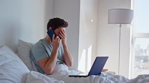 Verärgerter Manager spricht Handy-Sitzbett mit Laptop in Hotel-Nahaufnahme