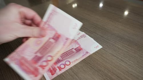 Counting Chinese currency: a close-up of a person organizing one-hundred yuan bills