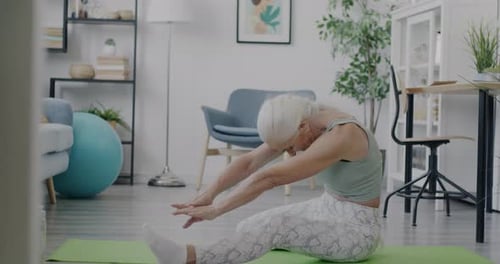 Senior Woman Stretching on Yoga Mat at Home