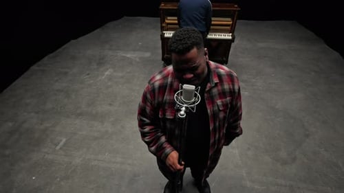 Singer And Pianist In A Black Studio Backdrop