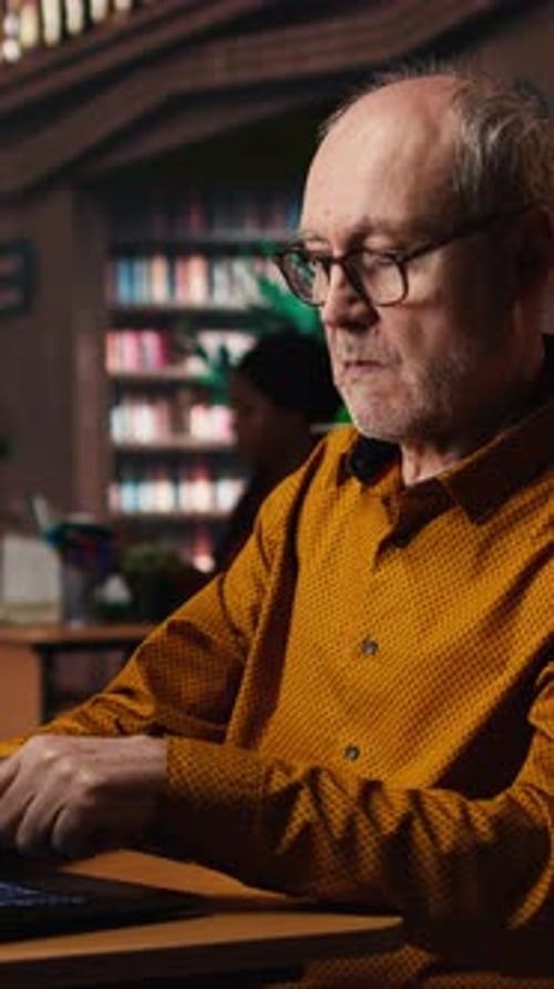 Vertical Video Focused Senior Guy Reading Academic Text on Laptop at the University