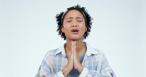 Hands, hope and nervous woman praying in studio for wish, good luck or spiritual help on white