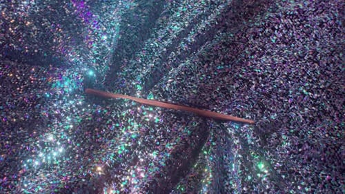 Gros plan d'un tissu à paillettes irisées chatoyantes avec un bâton en bois inséré dans un pli réfléchissant