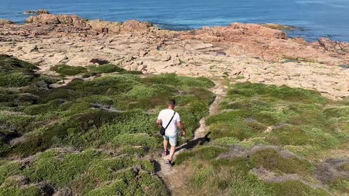 Rear View Of A Man Walking On The Rocky Headland To The Sea In Camarinas. - aerial