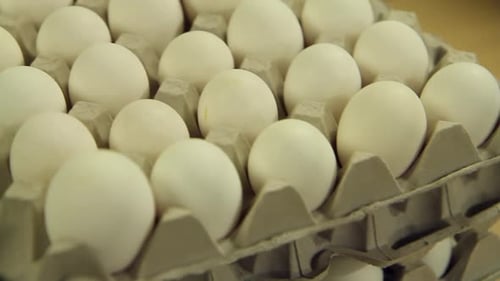 lot of white eggs in paper trays stacked in a tower one on top of the other