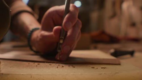 Hands crafting leather belt with hole punch