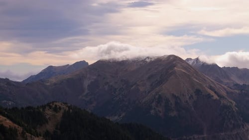 Des nuages blancs flottent dans le ciel et se rassemblent au sommet de la crête de la montagne à Agrafa, en Grèce