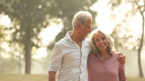 Aged Couple Enjoying A Joyful Walk in the Park During Sunset